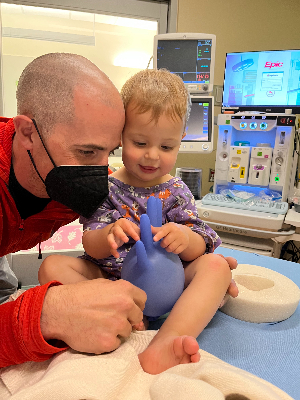 Nora awaiting sedation. The care team made her a glove balloon, which she loved.